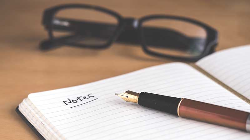 glasses, notebook, and a pen on a desk